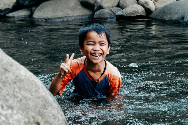 &nbsp;A boardly smiling young boy in a pool of gurgling water.&nbsp;Image by Rona Abdullah from Pixabay.&nbsp;